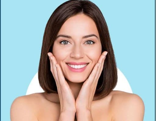 A young woman holds her face, free from skin imperfections