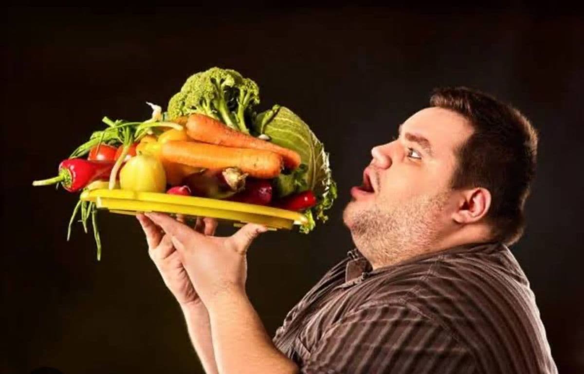 A heavyset man lifting a giant plate of vegetables