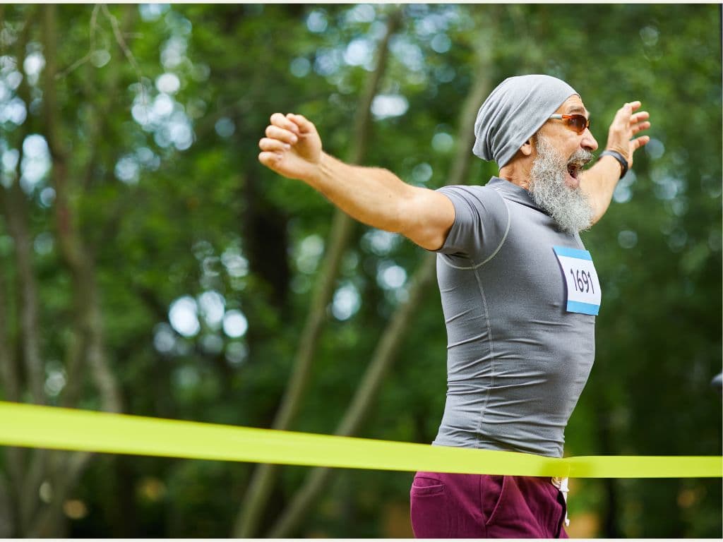 A man who is running through a yellow ribbon to win a race