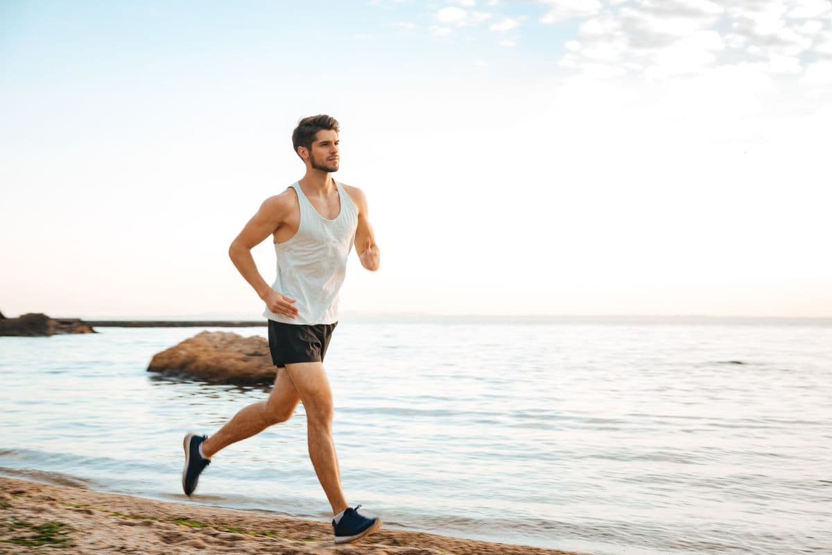 An athletic man running across the beach