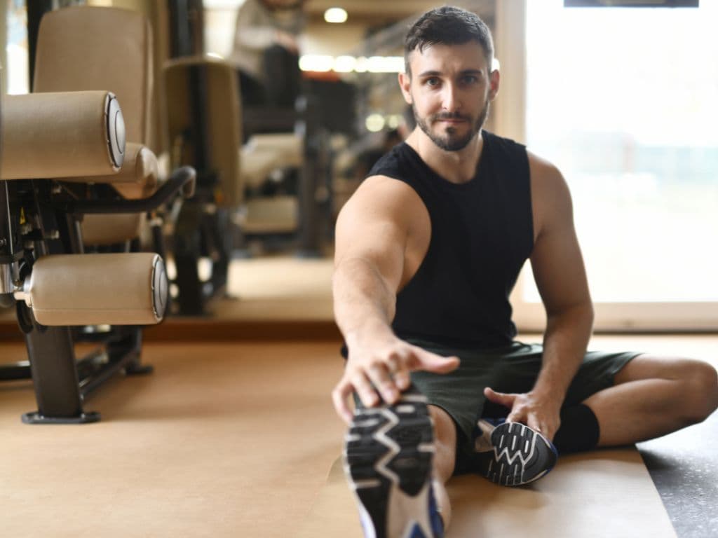 A man stretching his hand out to his foot