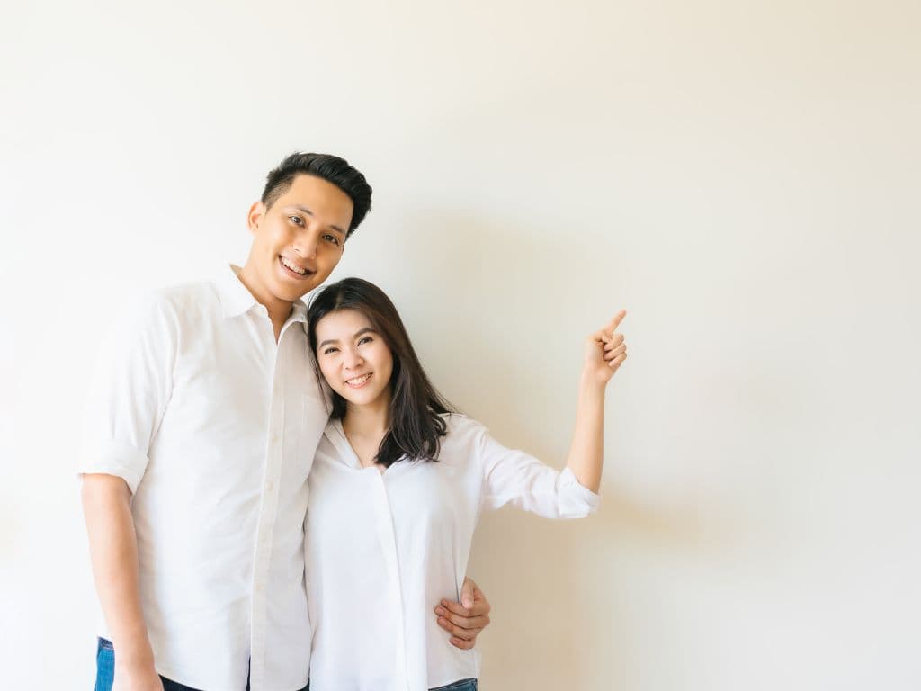 A couple holding each other closely while facing the camera and wearing white t-shirts