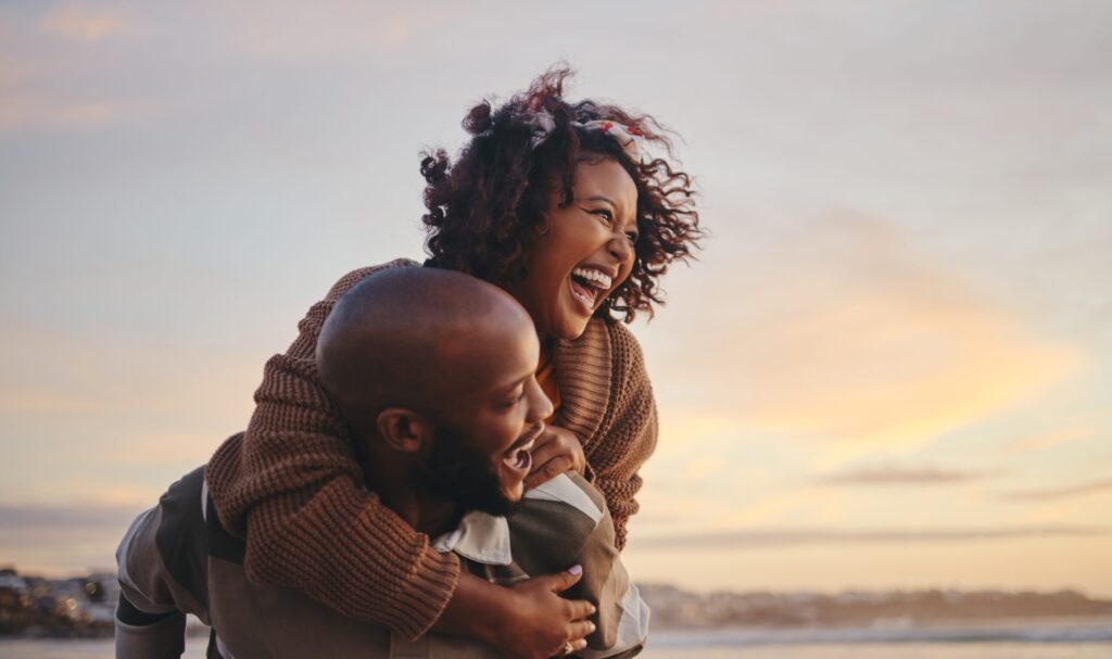 a man and woman laughing on the beach, representing glutathione on Vita Bella's blog